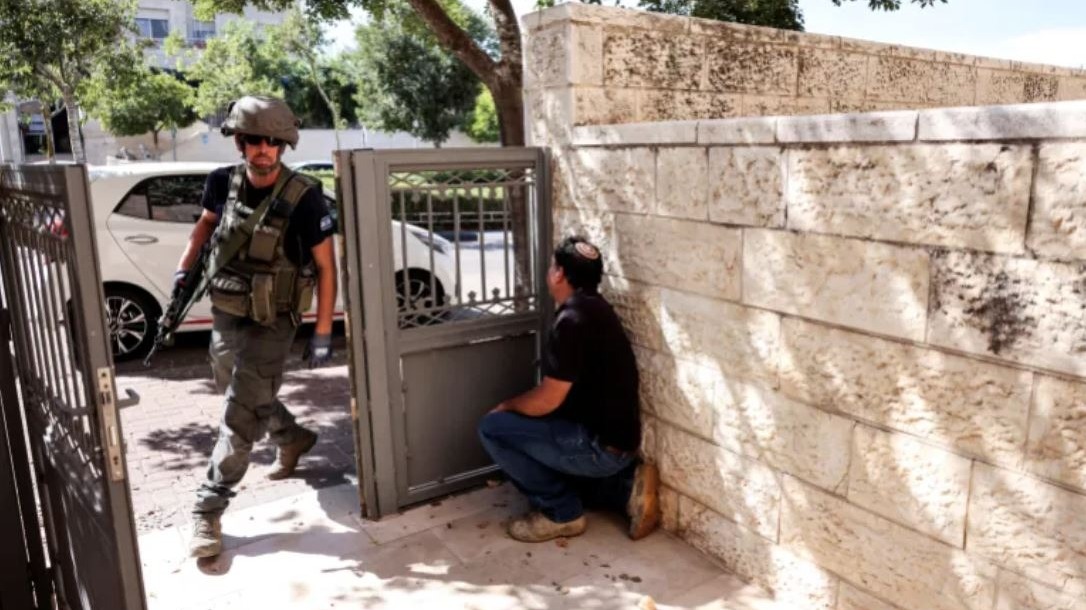 Местный житель прячется за стеной от боевика / фото Reuters