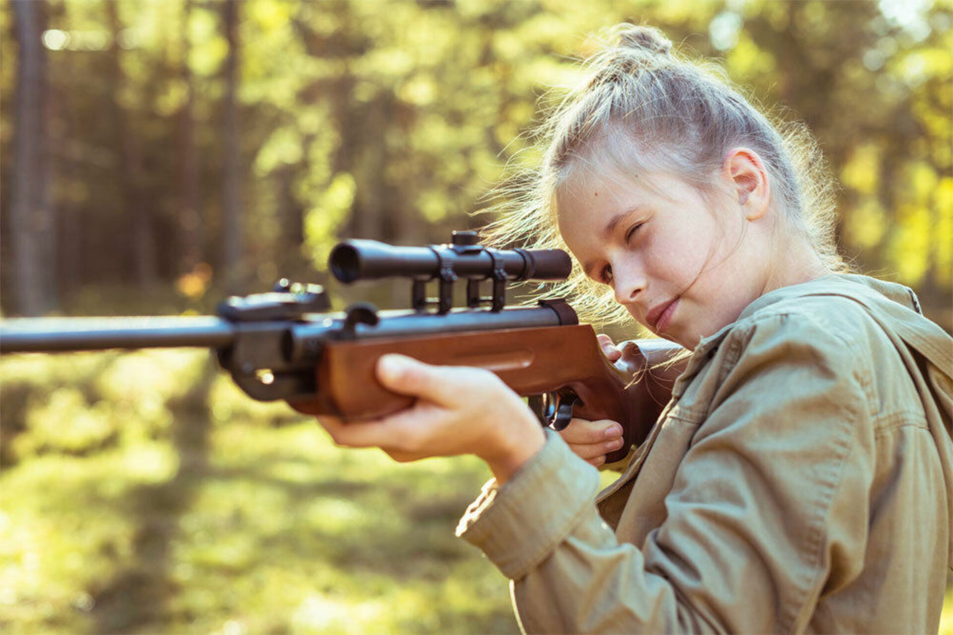 Стрелей. Оружие для детей. Выстрел из винтовки. Девушка целится из винтовки. Девочка с оружием.
