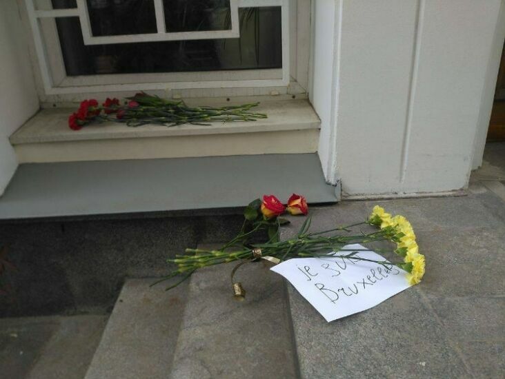 Москвичи несут цветы к зданию посольства Бельгии в российской столице