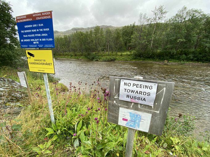 Знак на берегу пограничной реки, где туристы любят сделать фото