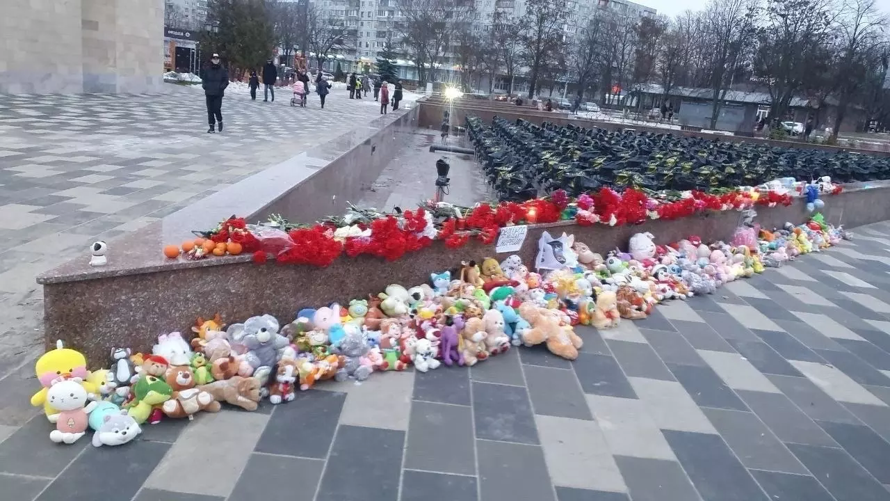 Люди несут цветы и игрушки к стихийным мемориалам
