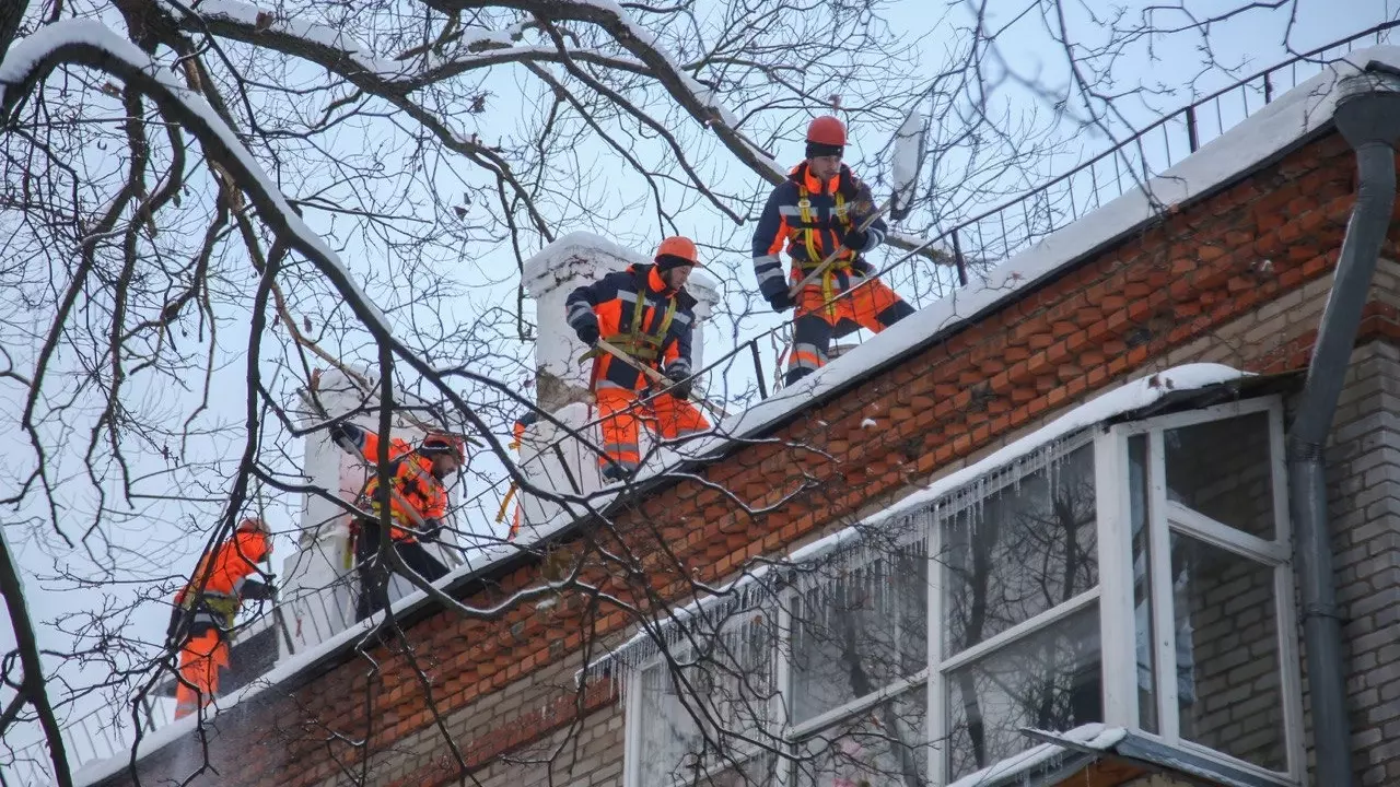 Альпинисты на крыше жилого дома устраняют последствия снегопада